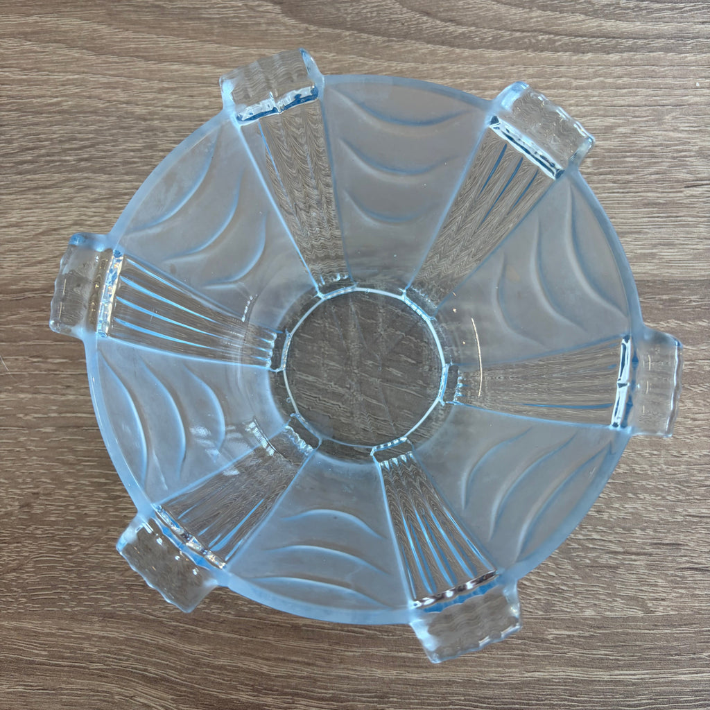 A clear glass bowl shown from a top-down view on a brown wood-grain surface.