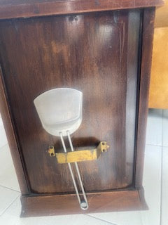 A vintage brass-toned metal arm, attached to a dark brown wooden wall panel.