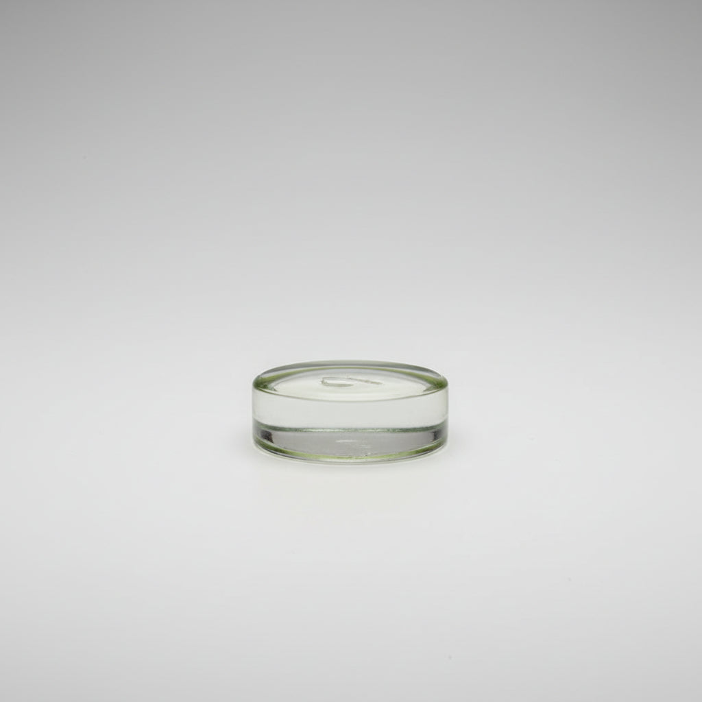 A small round glass frame with a green felt bottom depicting a miniature watercoloor